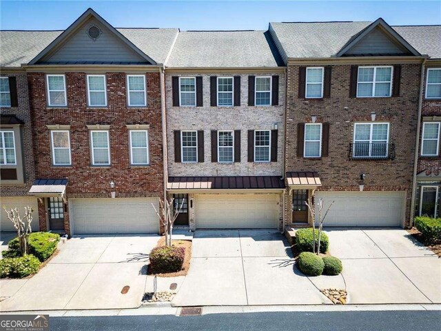 5749 Pine Oak Dr, Peachtree Corners, GA 30092 - view of property featuring an attached garage, concrete driveway, a standing seam roof, and brick siding