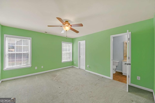 unfurnished bedroom with carpet, baseboards, ensuite bath, and a ceiling fan