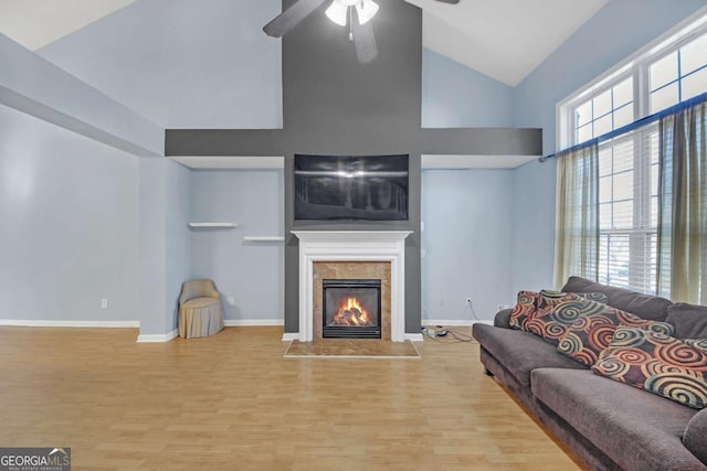 living area featuring baseboards, wood finished floors, a high end fireplace, and a ceiling fan