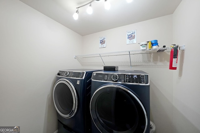 washroom featuring independent washer and dryer, rail lighting, and laundry area