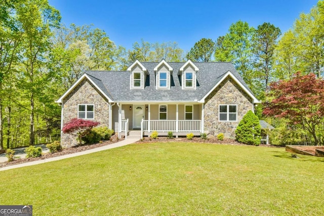 cape cod house featuring a porch, a shingled roof, stone siding, and a front lawn
