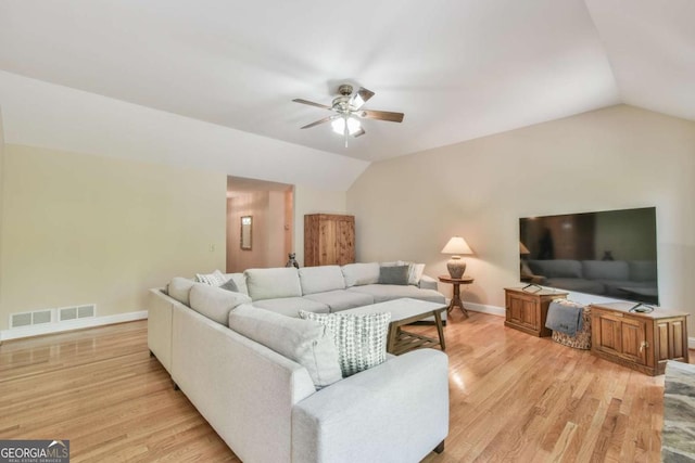 living area featuring light wood-style floors, a ceiling fan, visible vents, vaulted ceiling, and baseboards
