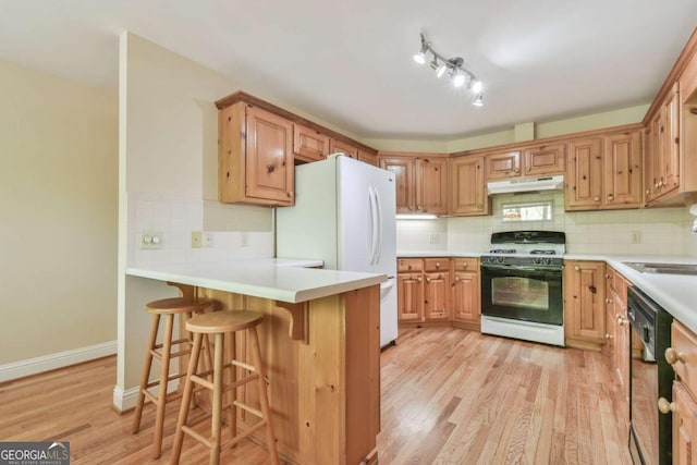 kitchen with tasteful backsplash, freestanding refrigerator, black dishwasher, gas range, and under cabinet range hood