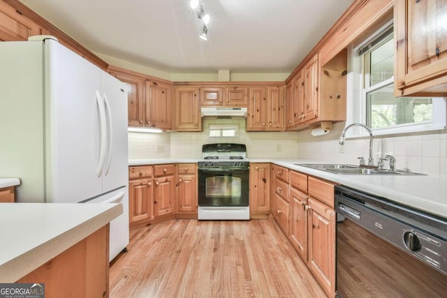 kitchen featuring freestanding refrigerator, under cabinet range hood, gas stove, dishwasher, and a sink