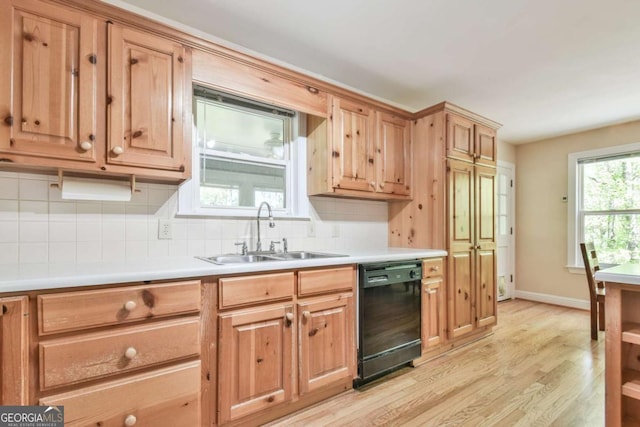 kitchen featuring dishwasher, light countertops, a sink, light wood finished floors, and backsplash