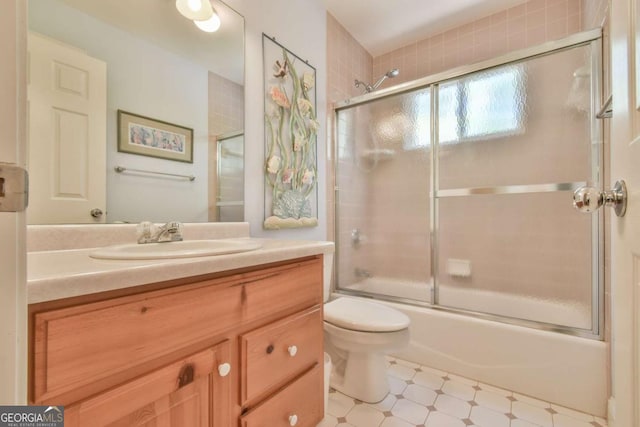 bathroom with combined bath / shower with glass door, toilet, and vanity