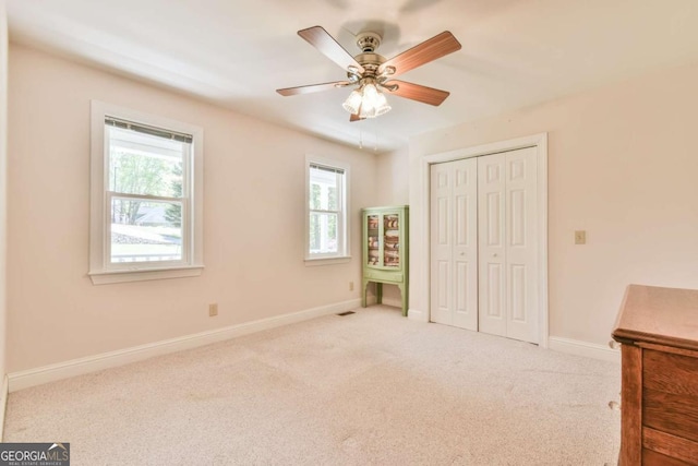 unfurnished bedroom with a closet, baseboards, visible vents, ceiling fan, and carpet flooring