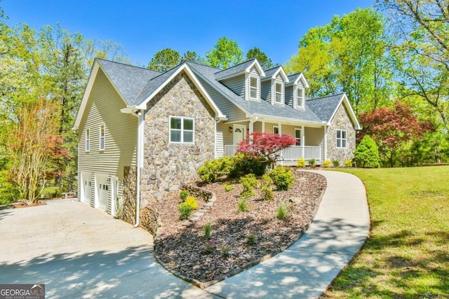new england style home with covered porch, a garage, stone siding, and a front yard