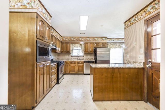 2237 W Elm St, Wrightsville, GA 31096 - kitchen featuring light stone counters, light floors, stainless steel appliances, a peninsula, and under cabinet range hood