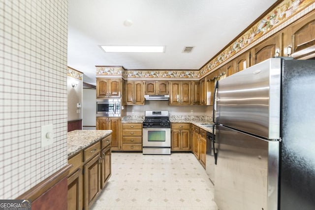 2237 W Elm St, Wrightsville, GA 31096 - kitchen with brown cabinets, light floors, appliances with stainless steel finishes, under cabinet range hood, and visible vents
