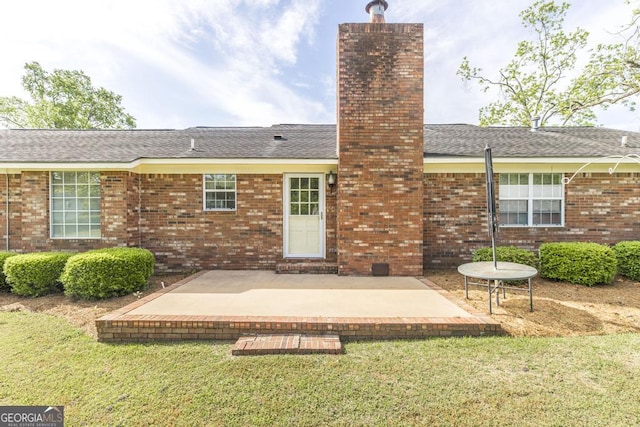 2237 W Elm St, Wrightsville, GA 31096 - back of property with a chimney, a lawn, a patio, brick siding, and roof with shingles