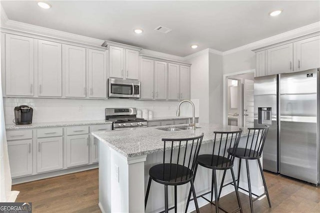 kitchen featuring ornamental molding, an island with sink, visible vents, appliances with stainless steel finishes, and a sink