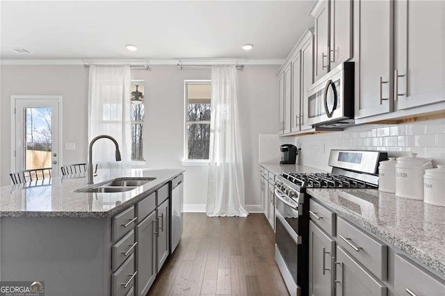 kitchen with a sink, appliances with stainless steel finishes, crown molding, light stone countertops, and gray cabinets
