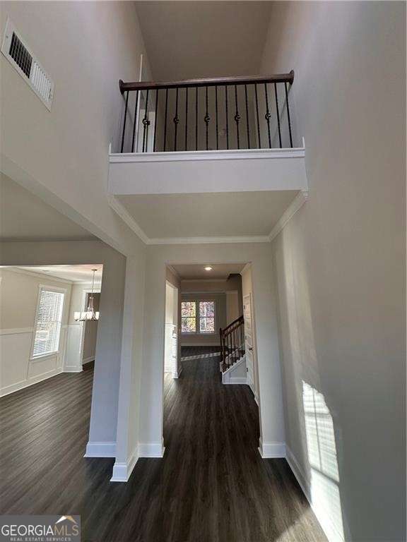 interior space featuring visible vents, a towering ceiling, an inviting chandelier, and wood finished floors