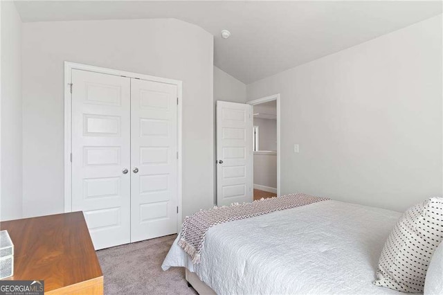 carpeted bedroom with a closet and lofted ceiling