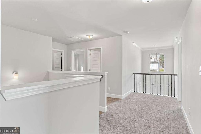 hall with baseboards, an upstairs landing, carpet flooring, and a chandelier