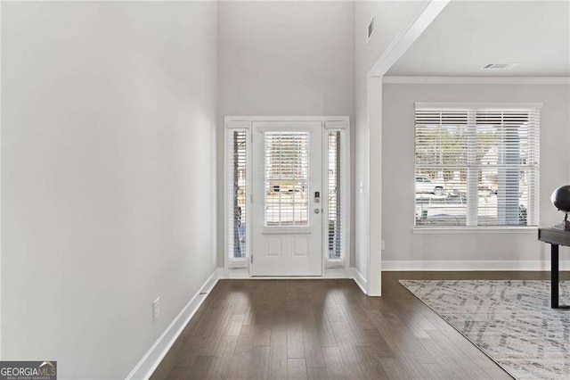 entrance foyer with visible vents, baseboards, ornamental molding, and wood finished floors