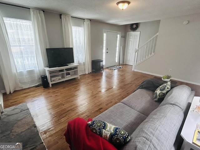 living room with a textured ceiling, stairs, and wood finished floors