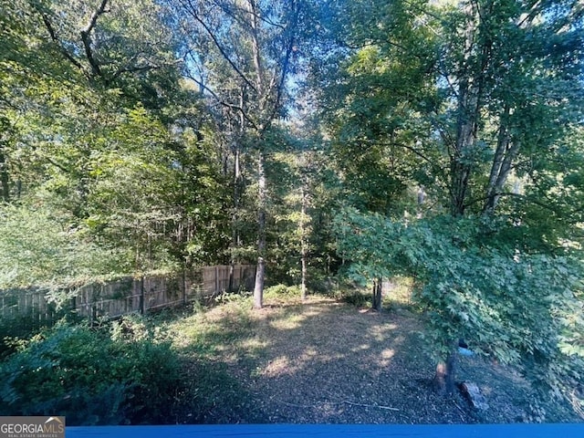 view of yard featuring fence and a wooded view