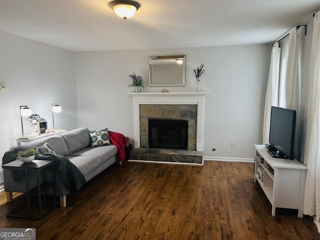 living area with baseboards, a fireplace, dark wood-style floors, and a textured ceiling