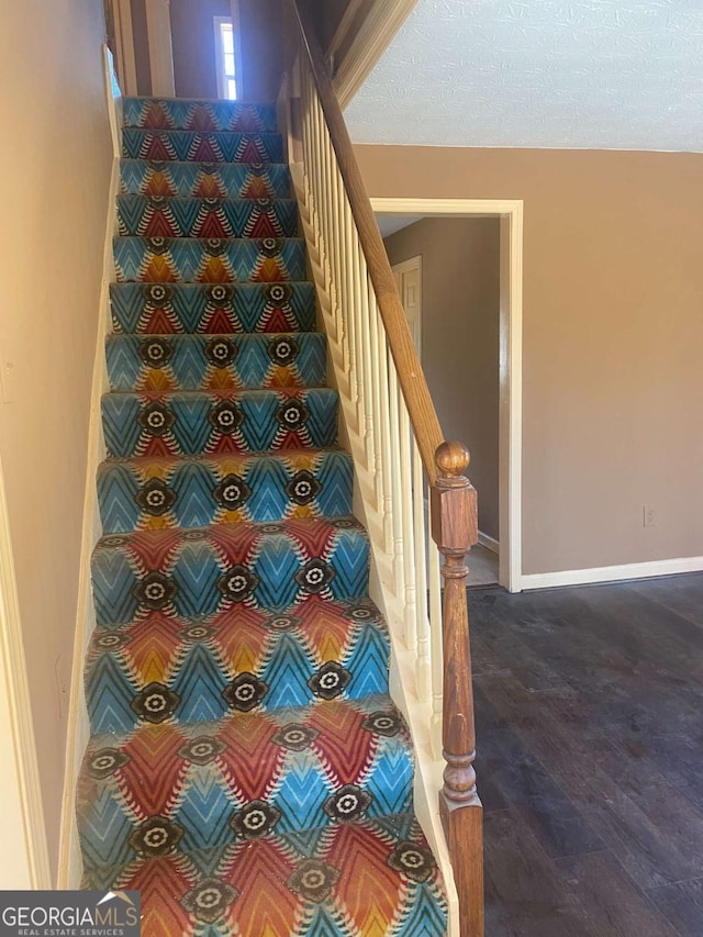 staircase featuring wood finished floors and baseboards