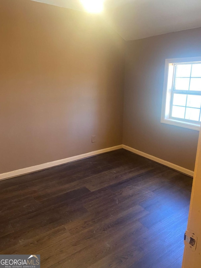 empty room with dark wood-style flooring and baseboards