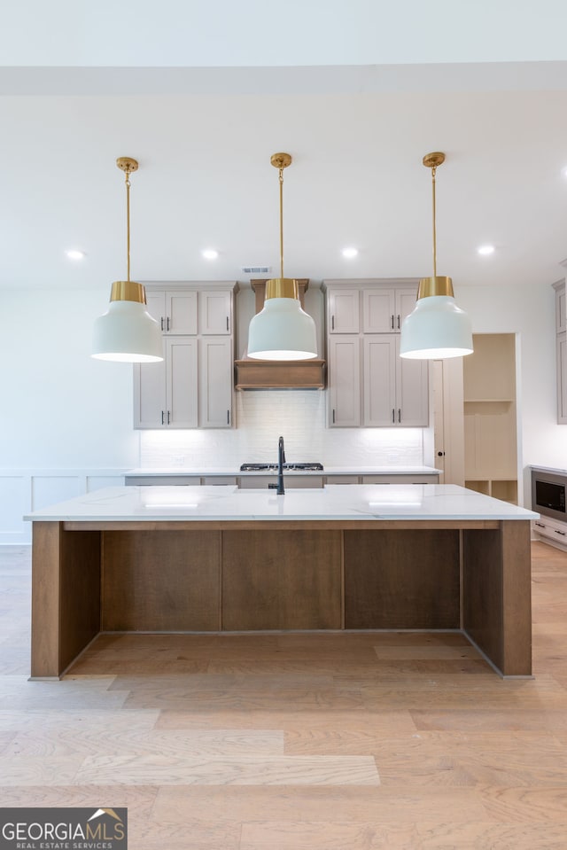 8415 Beryl Overlook, Gainesville, GA 30506 - kitchen with custom exhaust hood, light wood finished floors, a spacious island, and tasteful backsplash