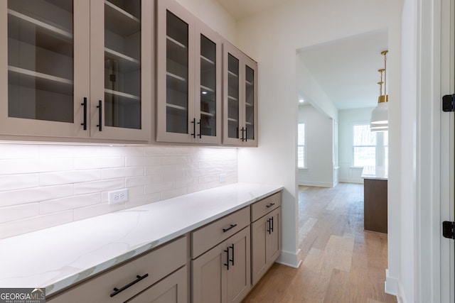 8415 Beryl Overlook, Gainesville, GA 30506 - kitchen with light wood-style floors, tasteful backsplash, light stone counters, and glass insert cabinets