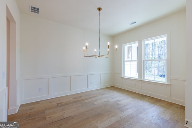 8415 Beryl Overlook, Gainesville, GA 30506 - unfurnished dining area with a decorative wall, wood finished floors, a chandelier, and wainscoting