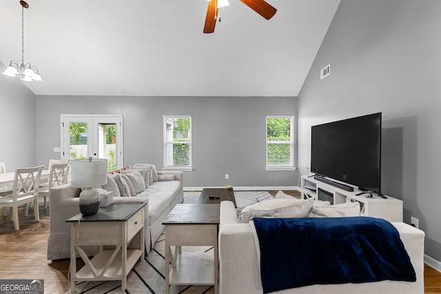 living room with a healthy amount of sunlight, baseboards, ceiling fan with notable chandelier, and wood finished floors