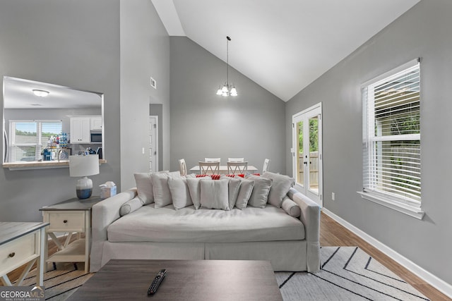 living area featuring an inviting chandelier, baseboards, wood finished floors, and high vaulted ceiling