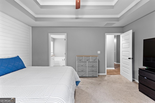 carpeted bedroom featuring crown molding, a tray ceiling, and ensuite bathroom