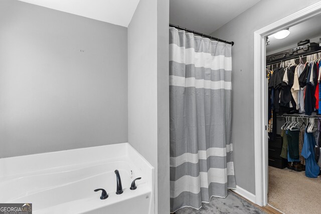 full bath featuring a walk in closet, a bath, and curtained shower