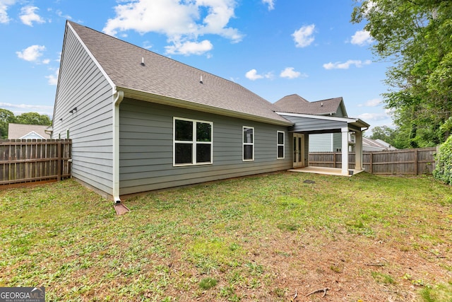 rear view of property featuring a fenced backyard, a patio area, a yard, and a shingled roof