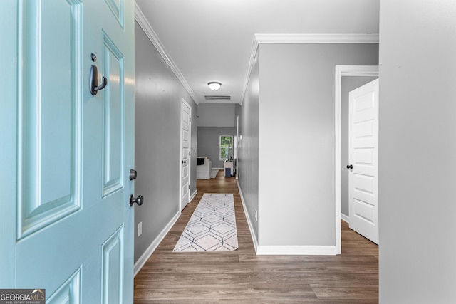 foyer entrance featuring baseboards, ornamental molding, wood finished floors, and visible vents