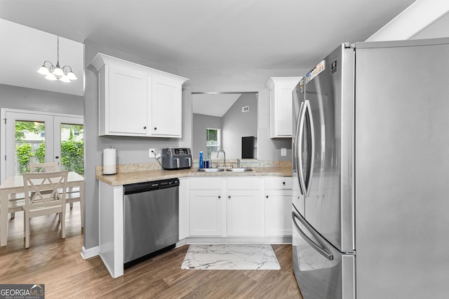 kitchen with wood finished floors, light countertops, white cabinetry, a sink, and stainless steel appliances