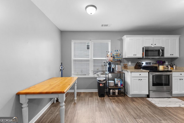kitchen featuring baseboards, white cabinetry, appliances with stainless steel finishes, and wood finished floors
