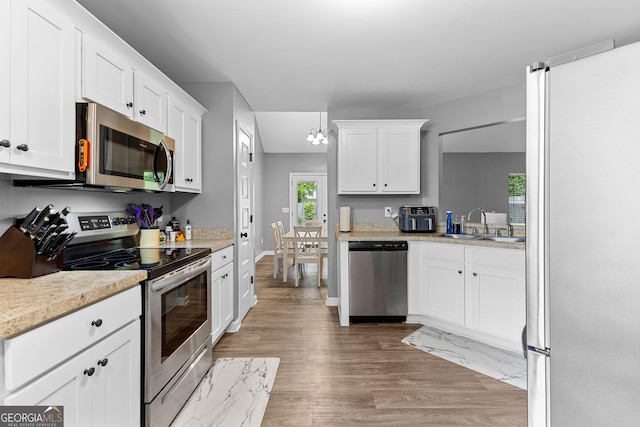 kitchen featuring wood finished floors, light countertops, white cabinets, a sink, and appliances with stainless steel finishes