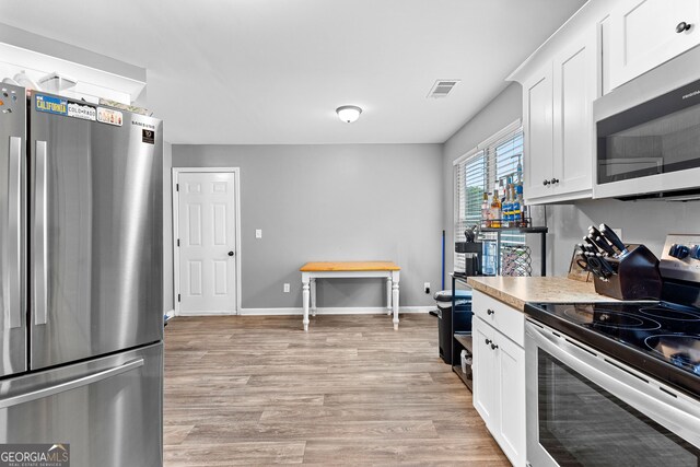 kitchen featuring visible vents, light countertops, white cabinetry, light wood-style flooring, and stainless steel appliances
