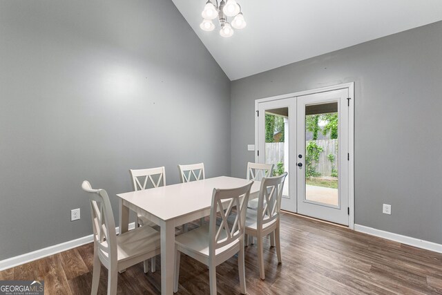 dining area featuring french doors, vaulted ceiling, wood finished floors, baseboards, and a notable chandelier