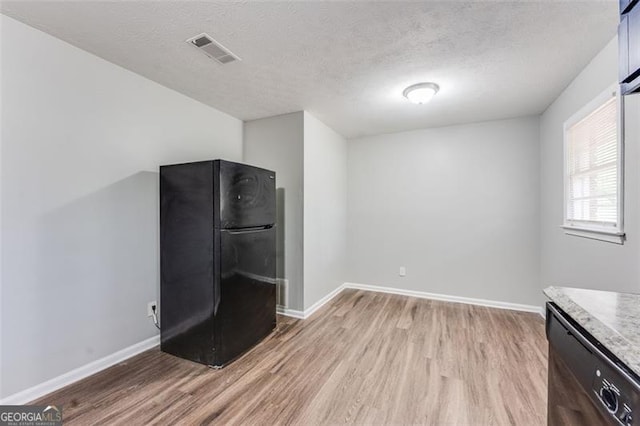 interior space with light wood finished floors, visible vents, baseboards, and black appliances