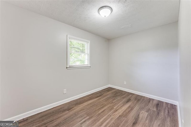 empty room with baseboards, wood finished floors, and a textured ceiling