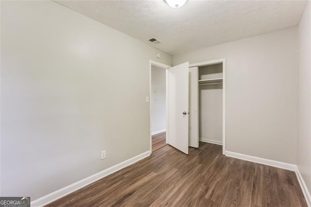 unfurnished bedroom with visible vents, a closet, baseboards, and wood finished floors
