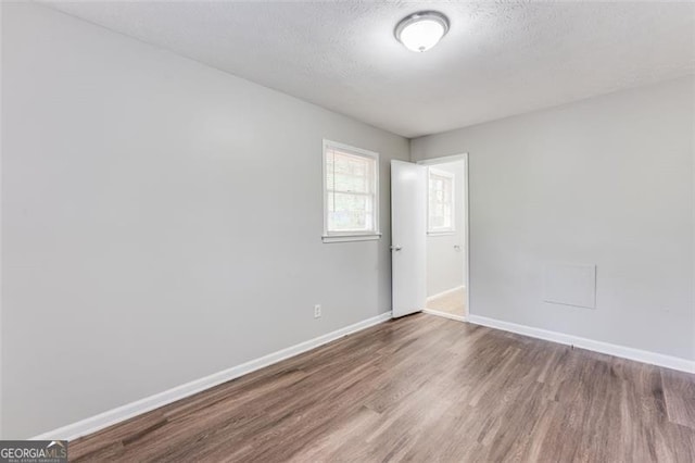 empty room featuring baseboards, a textured ceiling, and wood finished floors