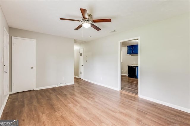spare room with wood finished floors, baseboards, a ceiling fan, and visible vents