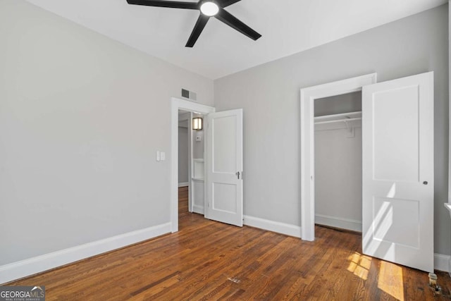 unfurnished bedroom featuring baseboards, wood finished floors, a closet, and visible vents
