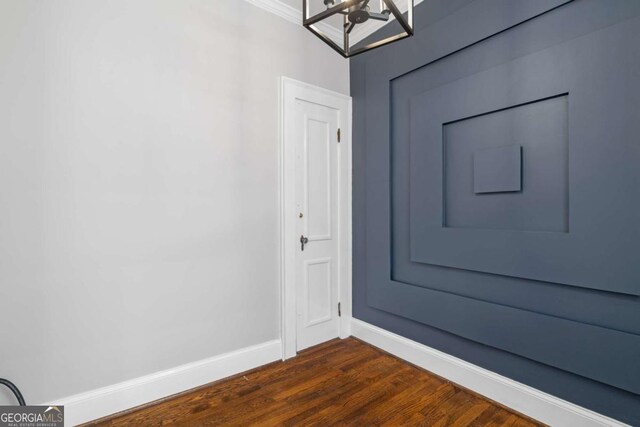 doorway with a chandelier, dark wood-style flooring, and baseboards