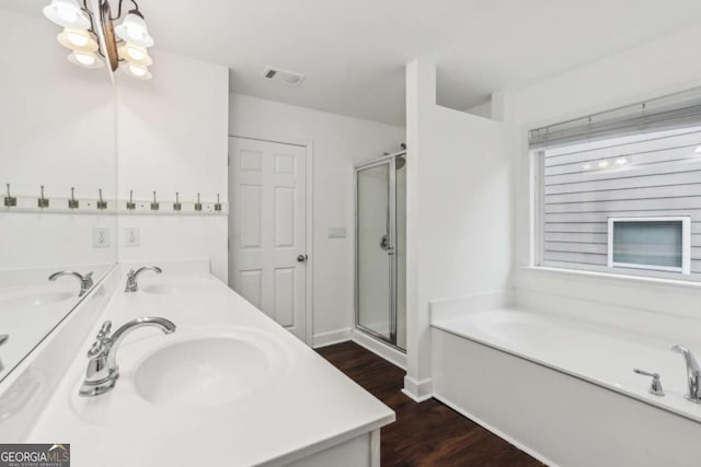 bathroom featuring a shower stall, wood finished floors, a sink, and visible vents
