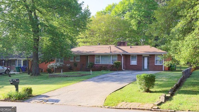 ranch-style home with a chimney, aphalt driveway, a front lawn, and brick siding