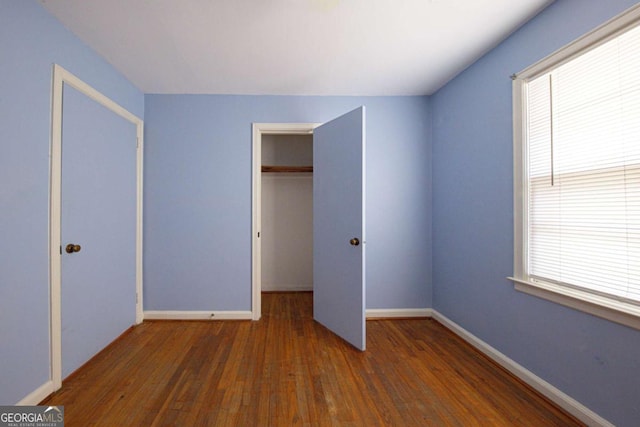 unfurnished bedroom with a closet, baseboards, and wood finished floors